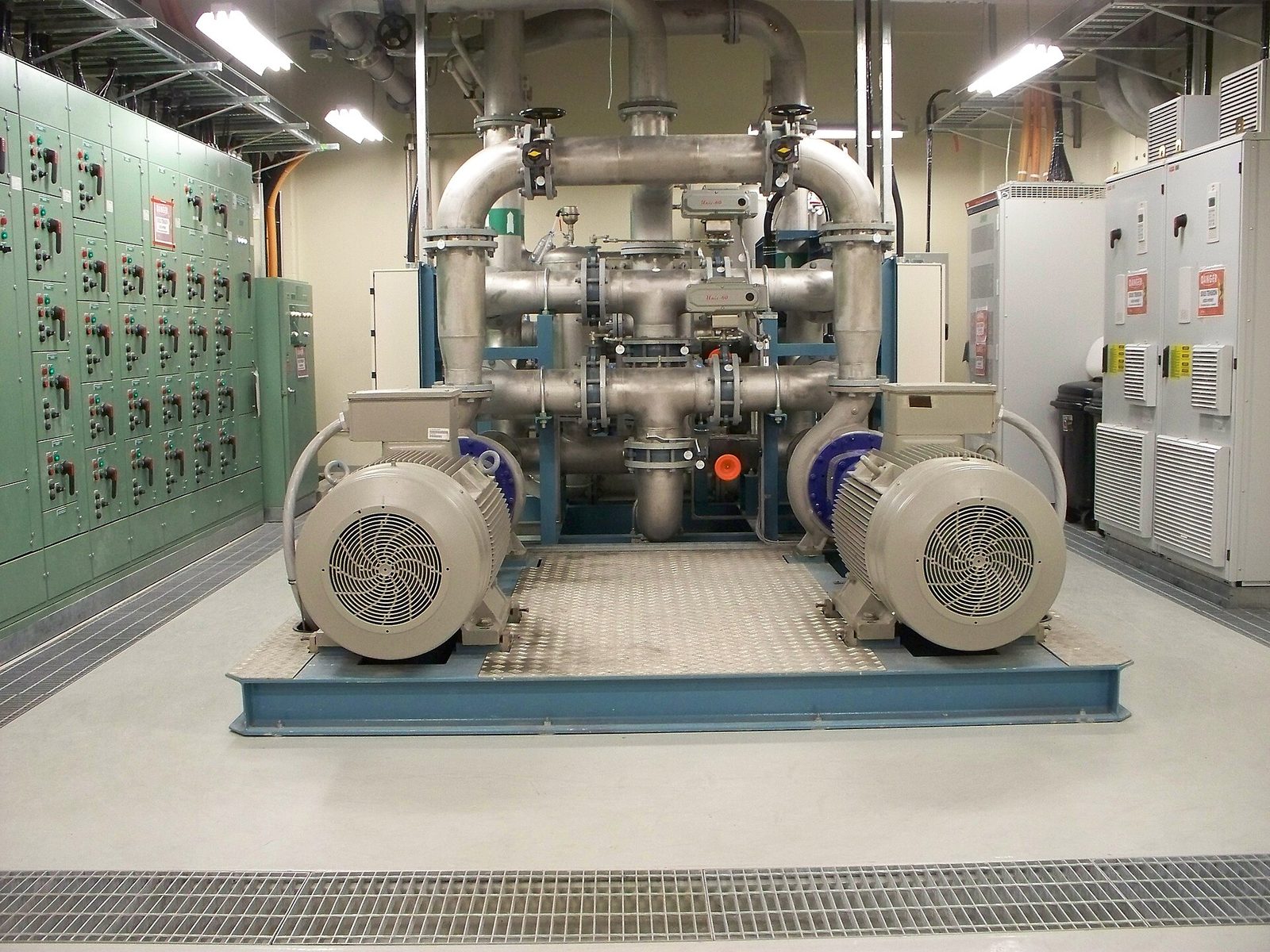 A duty and standby pump set with motors, pipework and control panels in a pump hall.